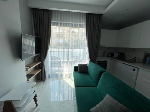 een woonkamer met een groene bank voor een raam bij The Yacht apartments in Alanya