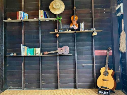 a wall with two guitars and books on it at Grandma’s House in Chiang Mai