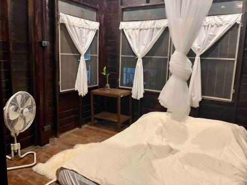 sypialnia z łóżkiem, wentylatorem i oknami w obiekcie Grandma’s House w mieście Chiang Mai