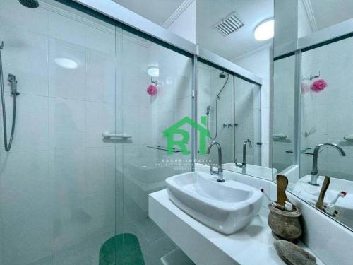 a bathroom with a sink and a glass shower at Apartamento dois dormitórios Praia das Pitangueiras in Guarujá