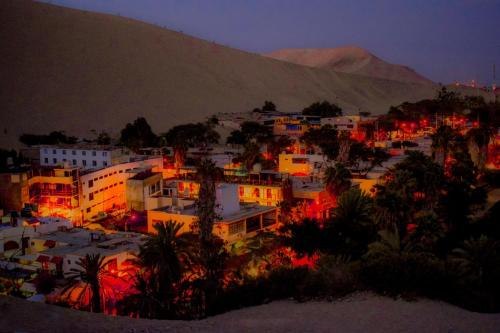 Eine Stadt leuchtete nachts mit einem Berg im Hintergrund in der Unterkunft HAWKA in Ica