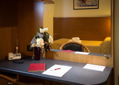 a room with a desk with a phone and flowers at ALLOGGI VITALE in Cesano Maderno