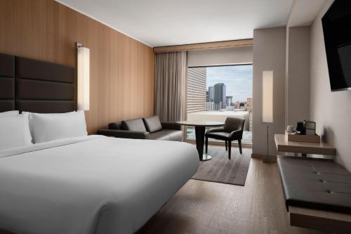 AC Hotel by Marriott Phoenix Downtown في فينكس: غرفة فندقية بسرير وطاولة مع كراسي