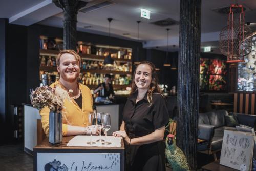 Ein Mann und eine Frau stehen an einer Bar mit Weingläsern. in der Unterkunft The Circus Hotel in Berlin