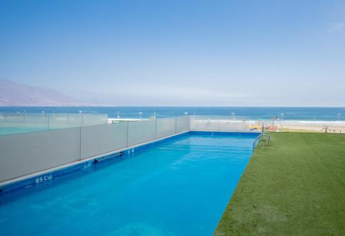 una gran piscina con el océano en el fondo en Acogedor y hermoso departamento en primera línea de Playa Brava, en Iquique