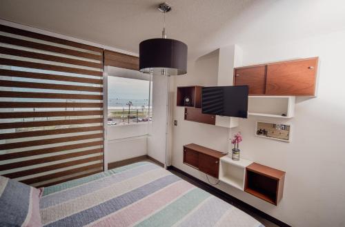 1 dormitorio con 1 cama, TV y ventana en Acogedor y hermoso departamento en primera línea de Playa Brava, en Iquique
