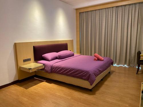 sypialnia z łóżkiem z fioletową pościelą i oknem w obiekcie The Floorspace Imperial Suites Apartment w mieście Kuching