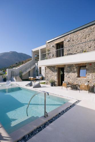 a villa with a swimming pool in front of a building at Mirthea Suites in Mírthios