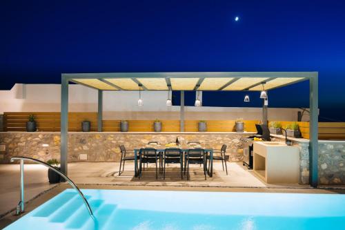 a patio with a table and chairs and a swimming pool at Mirthea Suites in Mírthios