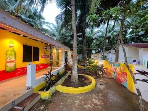 a building with a palm tree in a courtyard at Whoopers Party Hostel, Palolem in Palolem