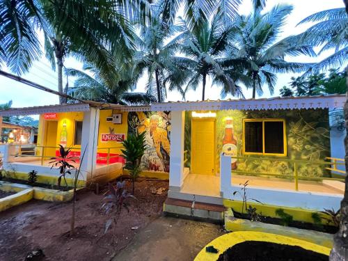 a house with a yellow door and palm trees at Whoopers Party Hostel, Palolem in Palolem