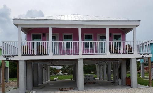 a pink house with a balcony on top of pillars at Old Wooden Bridge Resort & Marina in Big Pine Key