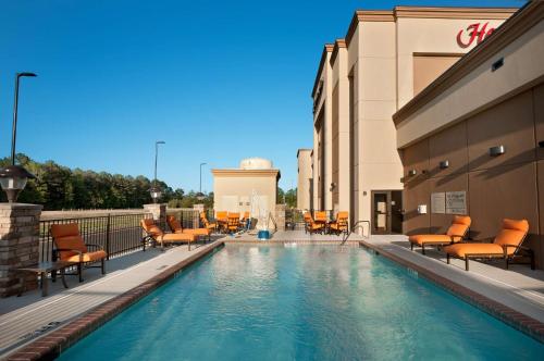 a swimming pool with chairs and tables on a building at Hampton Inn Magnolia in Magnolia