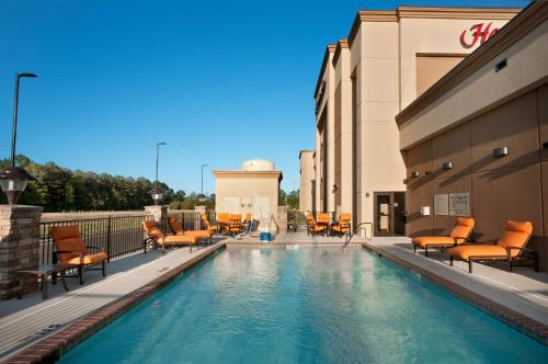 una piscina con sillas y mesas en un edificio en Hampton Inn Magnolia, en Magnolia