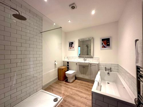 a bathroom with a tub and a toilet and a sink at Stylish 3Bed apartment with FREE PARKING in Heaton