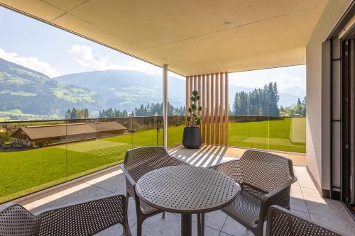 a patio with a table and chairs and a large window at Fankhauser Apartments in Ried im Zillertal