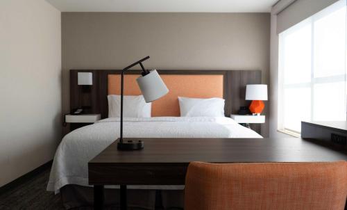 a bedroom with a bed and a desk with a lamp at Hampton Inn & Suites Seal Beach in Seal Beach