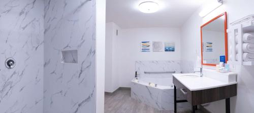 a bathroom with white marble walls and a sink and a mirror at Hampton Inn & Suites Seal Beach in Seal Beach