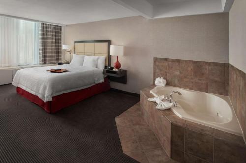 ein Hotelzimmer mit einem Bett und einer Badewanne in der Unterkunft Hampton Inn & Suites Milwaukee Downtown in Milwaukee