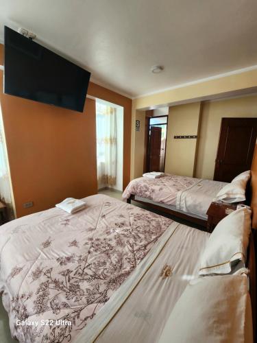 a hotel room with two beds and a flat screen tv at Hostal Capac in Ayacucho