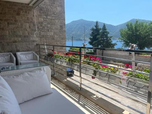 - un balcon avec un lit et des fleurs dans un bâtiment dans l'établissement Seafront Soleil apartment, à Dobrota