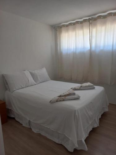 Un dormitorio con una cama blanca con toallas. en Suíte privativa na Barra da Tijuca proxima à praia, en Río de Janeiro