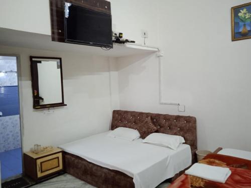 a bedroom with a bed and a tv on the wall at Hotel Swarajya Palace in Agra