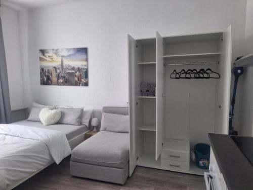 ein weißes Schlafzimmer mit einem Bett und einem Stuhl in der Unterkunft Studio Apartment 8 in Essen