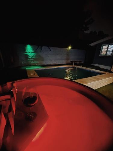 a glass of wine sitting next to a pool at night at CASA 1er piso completo con piscina temperada, tinaja y quincho próxima a Playa Sn Alfonso in Algarrobo