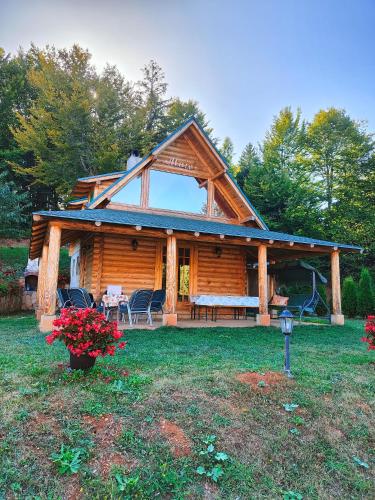 a log cabin with a porch and chairs in the yard at Vila Maja in Rudno