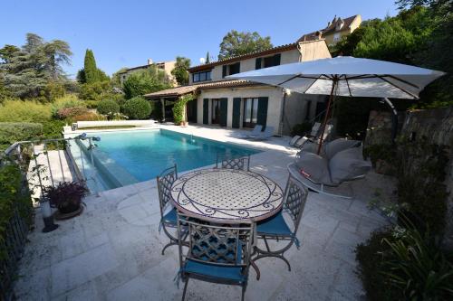 une table et des chaises avec un parasol à côté d'une piscine dans l'établissement Haute Vue - Luxury Villa - Private Pool & Panoramic View, à Montauroux