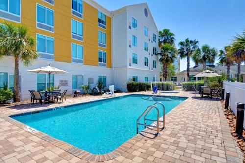 una piscina di fronte a un edificio con palme di Hilton Garden Inn Jacksonville Orange Park a Orange Park