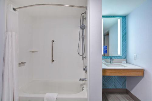 y baño con ducha, bañera y lavamanos. en Hilton Garden Inn Jacksonville Orange Park en Orange Park