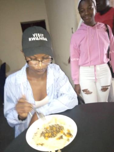 una mujer sentada en una mesa con un plato de comida en RUHENGELI,RWANDA, 