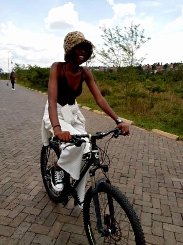 Eine Frau, die auf einer Backsteinstraße Fahrrad fährt. in der Unterkunft RUHENGELI,RWANDA 