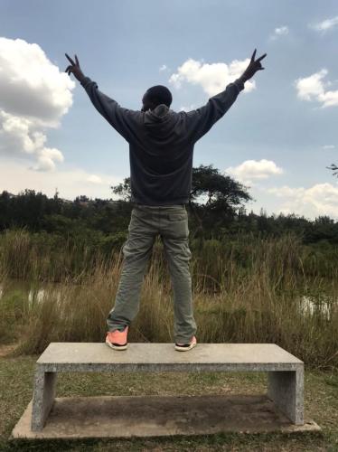 a man standing on a bench with his arms outstretched at RUHENGELI,RWANDA 