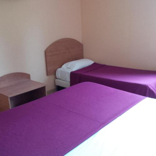 two beds in a room with purple sheets at Prim Hotel Reims nord in Witry-lès-Reims