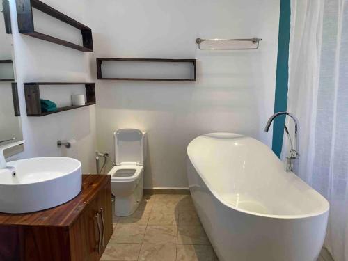 a bathroom with a tub and a toilet and a sink at Beautiful 3 rooms apartment, 2 beds & 1 dressing room in Flic-en-Flac