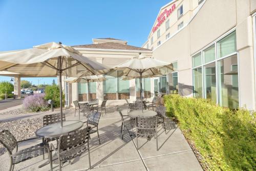 un patio con tavoli, sedie e ombrelloni di Hilton Garden Inn Laramie a Laramie