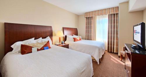 a hotel room with two beds and a flat screen tv at Hilton Garden Inn Laramie in Laramie