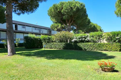 a building with a tree and flowers in a yard at Apartment 3 beds in Residence with swimming-pool bed and bath linen included in Marina di Bibbona