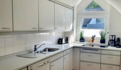 a white kitchen with a sink and a window at Apartment Bella Vista in Glücksburg