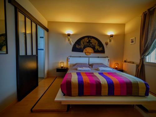 Le Belvédère : chambres et table d'hôtes في مونتميليان: غرفة نوم مع سرير وبطانية مخططة ملونة