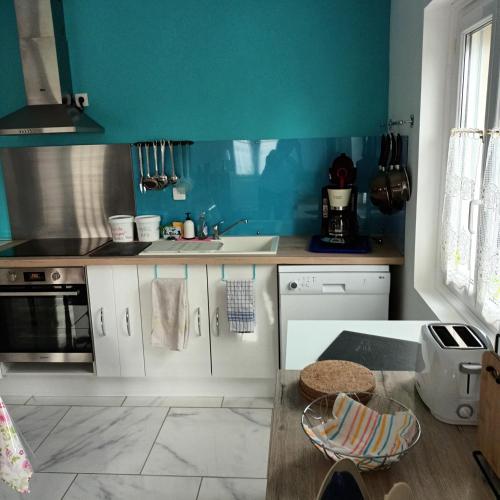 una cocina con armarios blancos y una pared azul en La petite maison Lavandin 