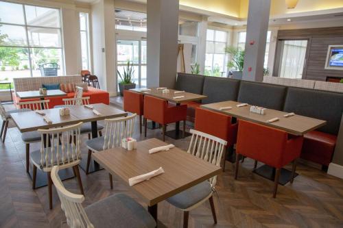 a restaurant with wooden tables and chairs and windows at Hilton Garden Inn Temple Medical Center in Temple