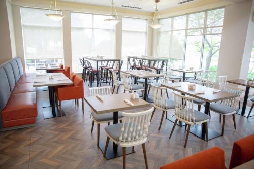 a restaurant with tables and chairs and windows at Hilton Garden Inn Temple Medical Center in Temple