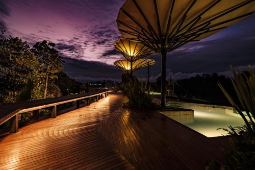 a boardwalk with an umbrella and a pool at night at Bosko in Guatapé