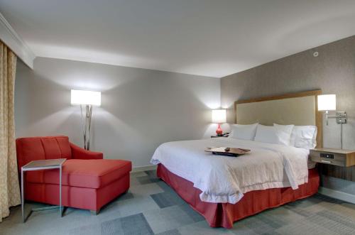 a hotel room with a bed and a red chair at Hampton Inn & Suites Springfield Downtown in Springfield