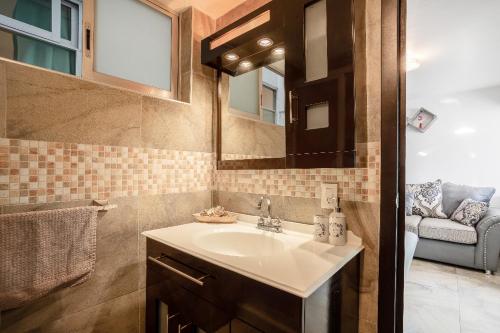 ein Badezimmer mit einem Waschbecken, einem Spiegel und einem Sofa in der Unterkunft Cuarto Yaqui - Seguridad - 10 min de Centros Comerciales y Zona Esmeralda - Empresas bienvenidas in Mexiko-Stadt