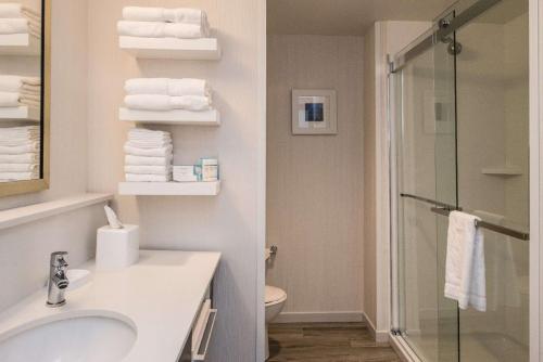 a bathroom with a sink and a shower with towels at Hampton Inn - Paragould in Paragould